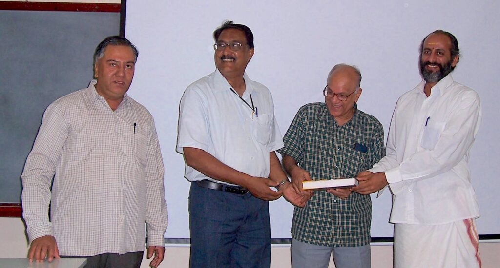 Three of the authors receiving a copy of Gaṇita-Yukti-Bhāṣā from Seshadri