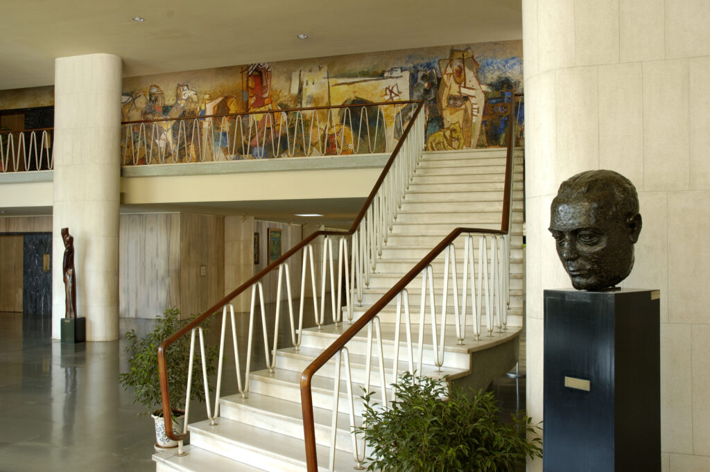 Marble stairs leading to the M.F. Husain mural and the library floor, with bust of Homi Bhabha on the right.